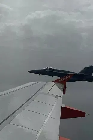 Испанский реактивный истребитель F-18, вид из окна самолета, сопровождает рейс Easyjet, направлявшийся из Лондона на испанский курортный остров Менорка / Испанский реактивный истребитель F-18, вид из окна самолета, сопровождает рейс Easyjet, направлявшийся из Лондона на испанский курортный остров Менорка /