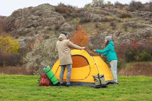 man and woman set up a camping tent man and woman set up a camping tent