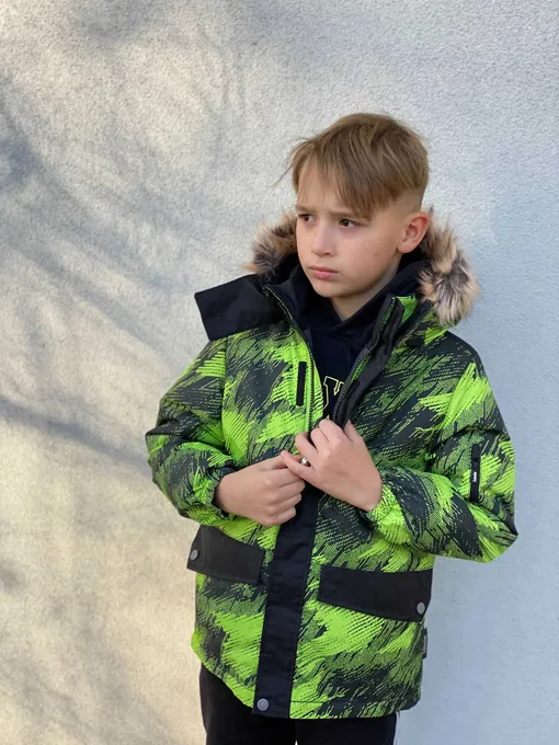 Светловолосый мальчик в зеленой и черной куртке