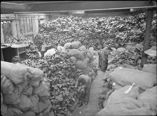 Склад утильсырья времен Второй мировой войны, заполненный изношенными армейскими сапогами.