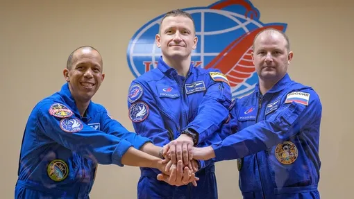 Экипаж «Союза МС-28» в составе Криса Уильямса из NASA (слева) и космонавтов Роскосмоса Сергея Кудь-Сверчкова (в центре) и Сергея Микаева позирует вместе 26 ноября 2025 года, за день до старта к Международной космической станции.
