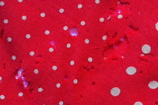 Дырки на ткани с принтом в горошек, сделанные молью