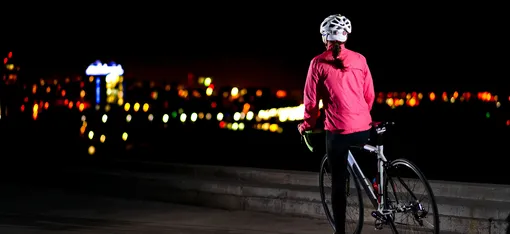 женщина на велосипеде ночь розовая куртка