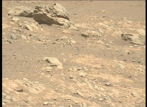 Марсоход NASA Perseverance снял это изображение камня необычной формы «Фиппсаксла» вдали в левом верхнем углу, которая, как предполагается, является метеоритом из-за высокого содержания железа и никеля.