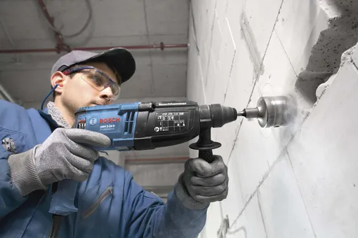 рабочий сверлит стену
