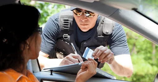 полицейский выписывает штраф женщине водителю