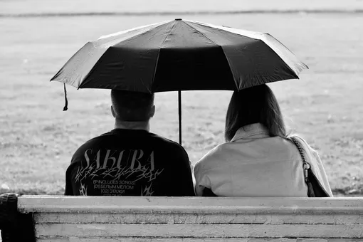 мужчина и женщина на скамейке под зонтом