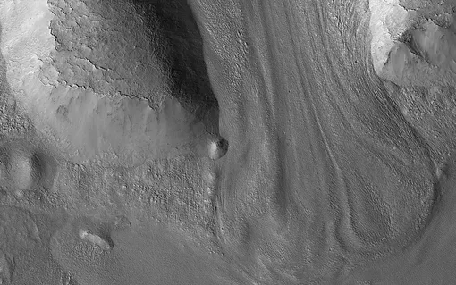 На этом снимке, сделанном космическим аппаратом NASA Mars Reconnaissance Orbiter (MRO), изображен ледник на Марсе, стекающий вниз между двумя хребтами. Согласно последним исследованиям, ледники на Марсе по крайней мере на 80% состоят изо льда.