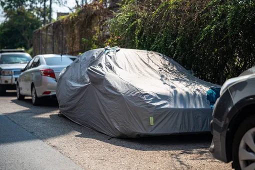 автомобиль на улице под защитным чехлом автомобиль на улице под защитным чехлом