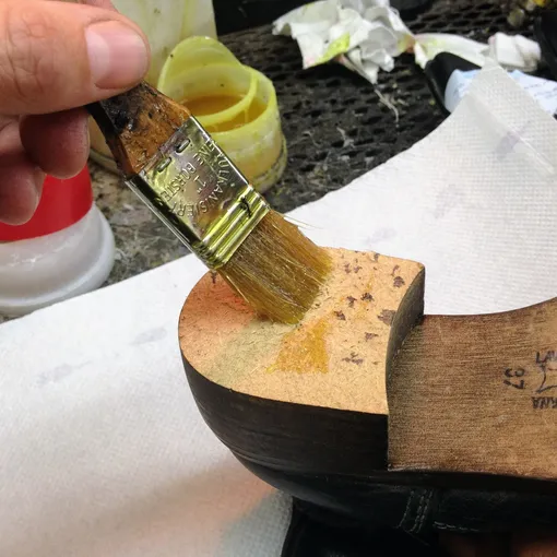 Мастер кистью наносит клей на подошву