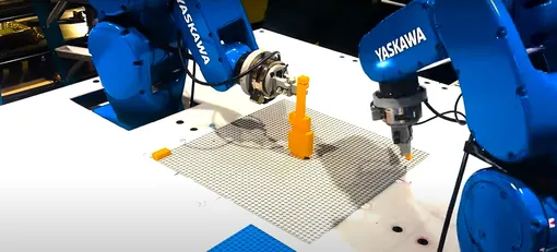 Два робота строят объект из Lego. Два робота строят объект из Lego.