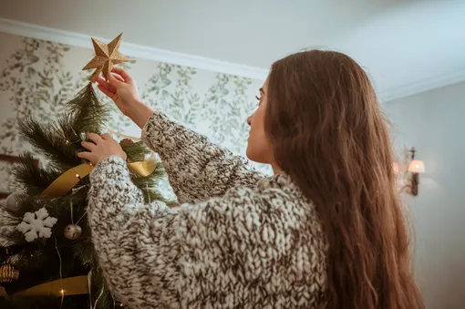 Девушка украшает елку на Новый год
